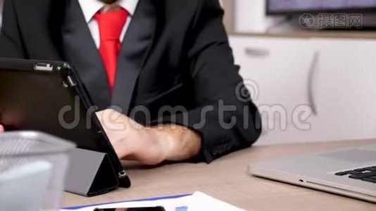在平板电脑的秘密上，用黑色西装和红领带紧紧抓住男人的双手视频