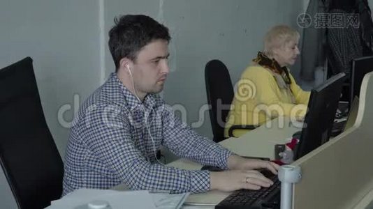 带着耳机的年轻人在办公室的电脑里工作视频