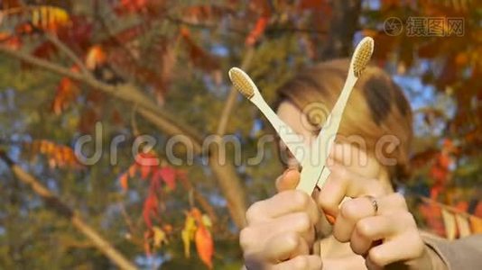 金黄短发的小女孩，在秋天阳光明媚的天气里，拿着一把竹制牙刷在户外视频