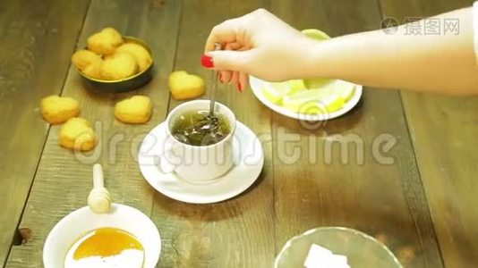 一个女人把刚泡好的绿茶和勺子混合在白色的杯子里视频