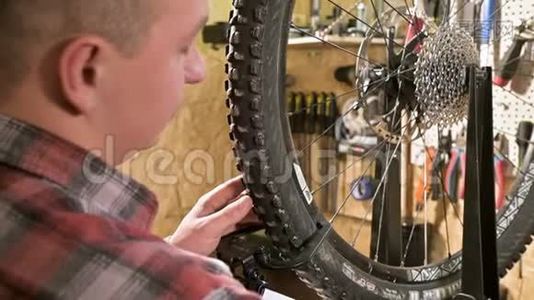 年轻的男自行车修理工在车间的一个支架上用专门的扳手拧紧车轮的辐条视频