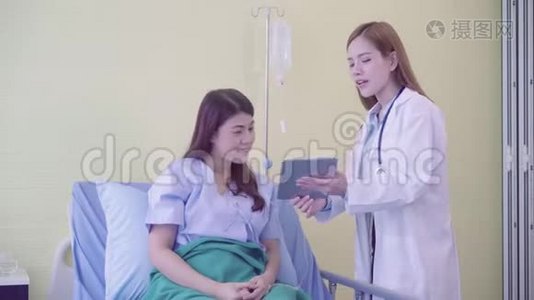 美丽聪明的亚洲医生和病人讨论和解释一些东西与药片在医生手中。视频