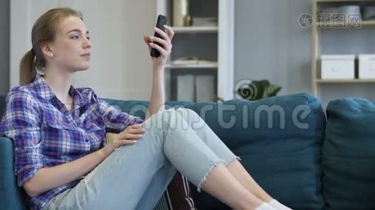 年轻女子在沙发上放松时打电话视频