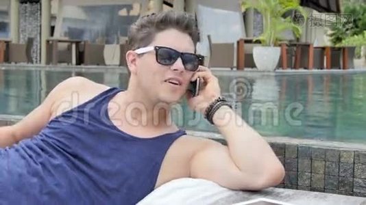 在热带度假胜地，一个坐在池边的闲人在用手机聊天。视频