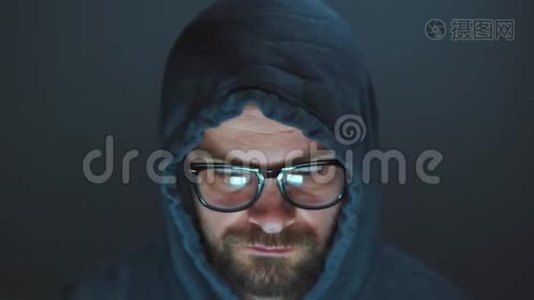 戴着头巾的男黑客和戴着眼镜在黑暗的办公室里用电脑工作。 网络犯罪概念视频