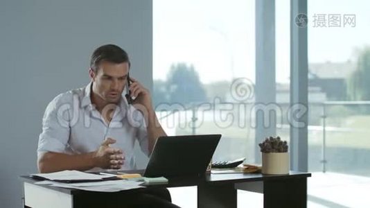 在笔记本电脑工作的商人。 专心致志的男人在说手机。视频
