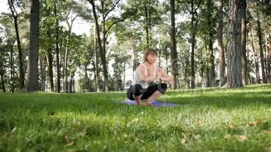 四K镜头，40岁的女人在当地公园的垫子上做健身运动。 照顾他们的精神和视频