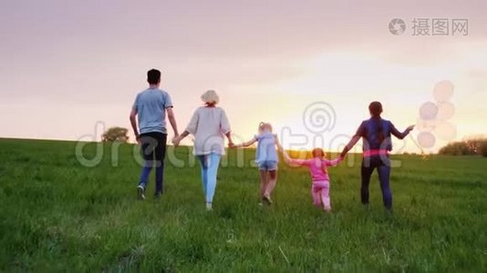 一个带着孩子的大家庭正沿着绿色的草地走向日落视频