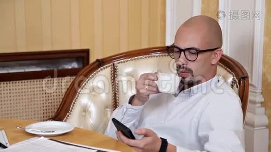 办公室里餐桌上的秃头男人在喝咖啡视频