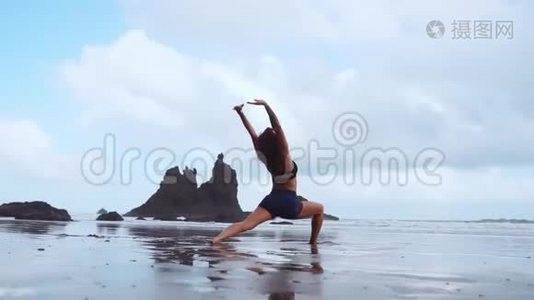 快乐的年轻女子在日落时在海滩上练习瑜伽。 健康活跃的生活方式理念.. 慢动作视频
