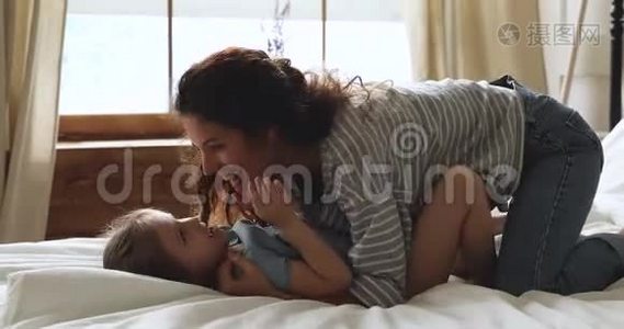 无忧无虑的妈妈和小女儿在床上玩得开心视频