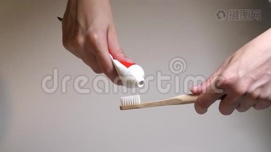 把牙膏从试管里挤到木制牙刷上。 带有新鲜白色牙膏的牙刷白色刚毛。视频