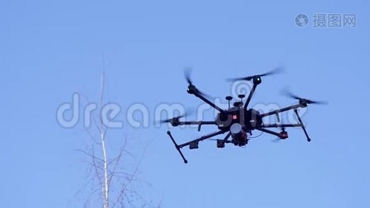 黑色相机无人机飞行与可见的推进器运动和闪光灯在蓝天背景。 剪辑。 小型视频