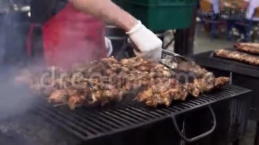 男人在烧烤烧烤架上为他的朋友在夏季户外聚会上煮肉。 用热炭煮猪肉。 特写视频