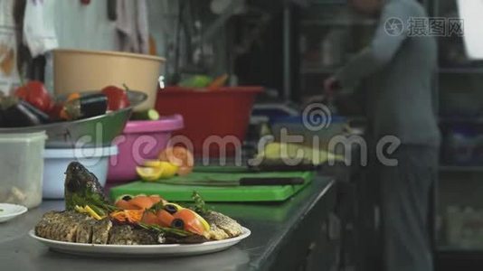 餐厅或咖啡厅的厨房里有烤鱼和蔬菜，厨师在后台工作视频