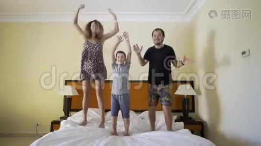 幸福的一家人在床上跳。 幸福的家庭观念。 爸爸，妈妈和小男孩跳在床上视频