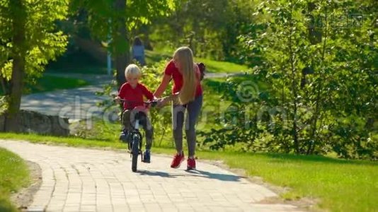 一个年轻女子慢镜头教她的小儿子骑自行车视频