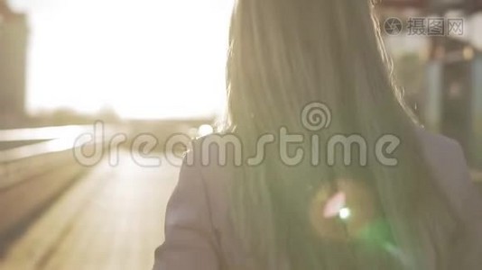 美丽的金发女郎对着镜头微笑，日落时转身视频