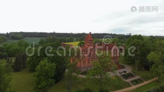 在拉脱维亚的老城堡庄园上空飞行-夏季从上面俯瞰的Jaunmoku皮尔和周围的绿树视频