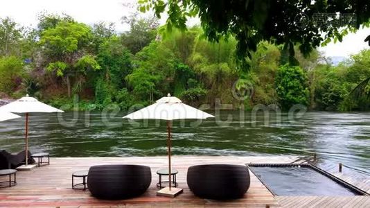 泰国葵坎查纳布里河附近度假胜地的海滨木筏上的躺椅或日光浴床和雨伞。 旅游和度假视频