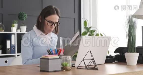 女商人在手提电脑工作时检查文件视频