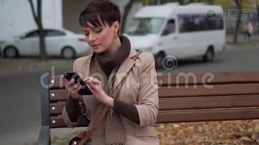 年轻女性坐在长椅上使用智能手机视频
