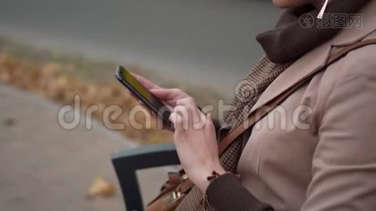 年轻女性坐在城市的长椅上使用智能手机视频