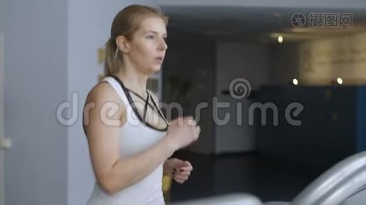 适合女士有氧训练和健身房的侧视图。 女人在跑步机上跑步。视频