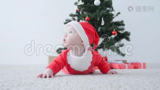 圣诞节的概念。 穿着圣诞老人服装可爱的宝宝，看着礼物视频
