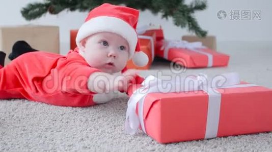 圣诞节的概念。 穿着圣诞老人服装可爱的宝宝，看着礼物视频