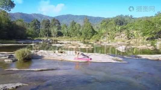 女孩用瑜伽对抗平静的河流在岩石中流淌视频