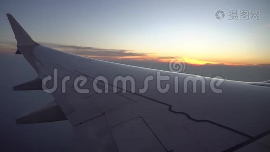 从飞机窗口日落。 观橙色的太阳，飞机的翅膀，黑暗的天空和云彩。视频