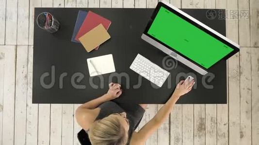 年轻女子在她的办公桌上用电脑工作。 绿色屏幕模拟显示。视频