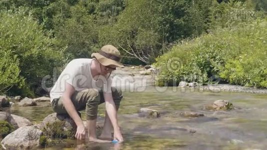 夏天爬山时，旅行的人从山上的河里拿一瓶水视频