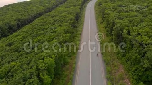 空中射击-无人驾驶飞机在公路和森林上空移动，附近有大海视频