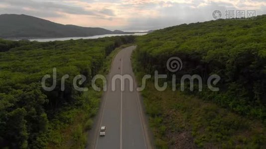 空中射击-无人驾驶飞机在公路和森林上空移动，附近有大海视频