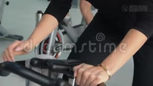 健身妇女在自行车课上进行室内自行车训练。 团体运动的人在自行车健身房旋转自行车。 心脏培训视频