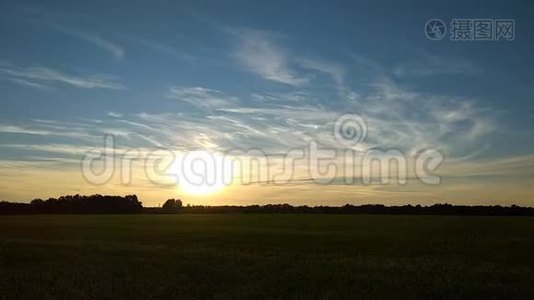 在日落时间附近的渐变天空上，在以太阳为中心的上空飘散的云的时间流逝的片段视频