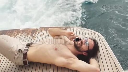 自由的生活。 英俊而富有的人日光浴的肖像。 从私人游艇上开枪。视频