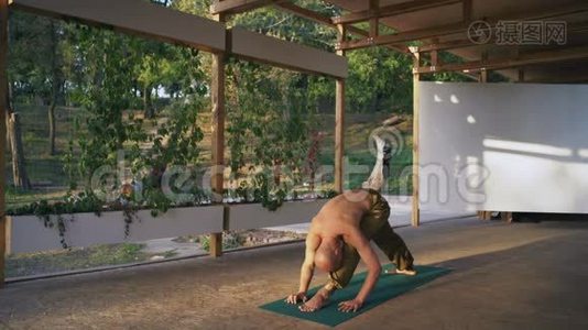 光着脚、裸着躯干的年轻人在城市公园的木制Pomo上表演瑜伽体式视频