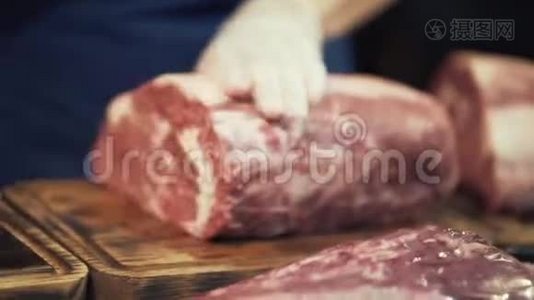 在白色防护手套中特写肉手，准备一大块肉供烹饪或销售。 行动。 屠夫视频