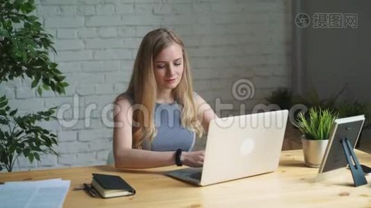 一位有创意的女士坐在办公桌前的肖像。 使用笔记本。 她坐在轻盈现代的办公室里视频
