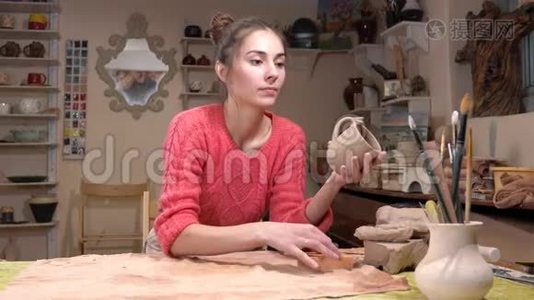 一般的看法，一个女孩陶匠选择一个适当的流苏，以微调生粘土杯在陶器车间。视频