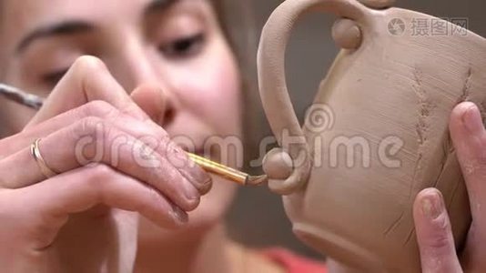 女陶工的特写强调细节，使用流苏在她手中的生泥杯。视频