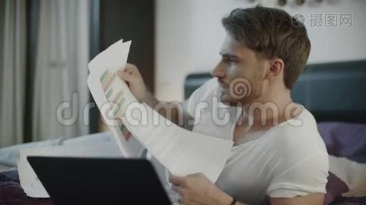 在沙发上拿着文件和笔记本电脑的严肃男人视频