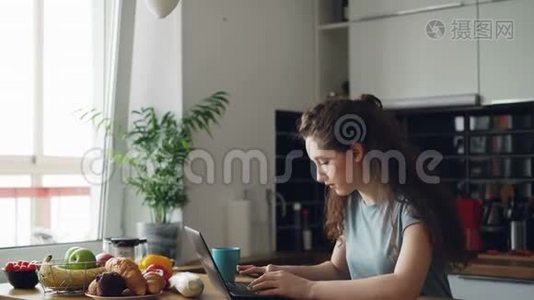 早上早餐时，一位精力充沛、开朗的年轻女士在厨房打手提电脑视频