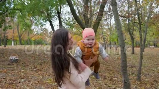 年轻的妈妈和宝宝在秋天的公园户外玩得很开心，快乐的家庭享受大自然视频