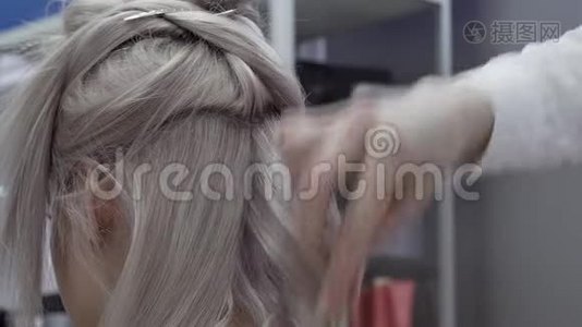 美发师为一个金发的客户女孩制作美丽优雅的卷发视频