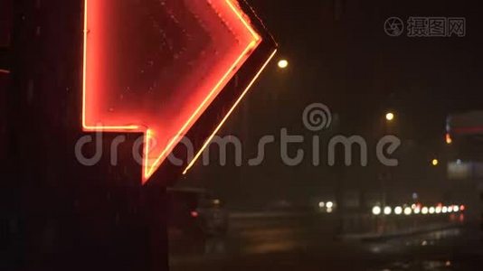 雪片在夜间落在红色霓虹灯的发光箭头引导到加油站与道路的背景。视频