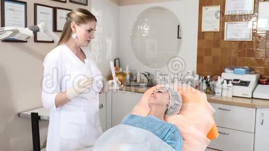 保健诊所的美容师与一位女性客户交谈，解释面部手术的细节，并显示无菌视频